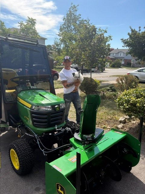 Jay Stortini with his dog beside his John Deere tractor and its snowblower attachment